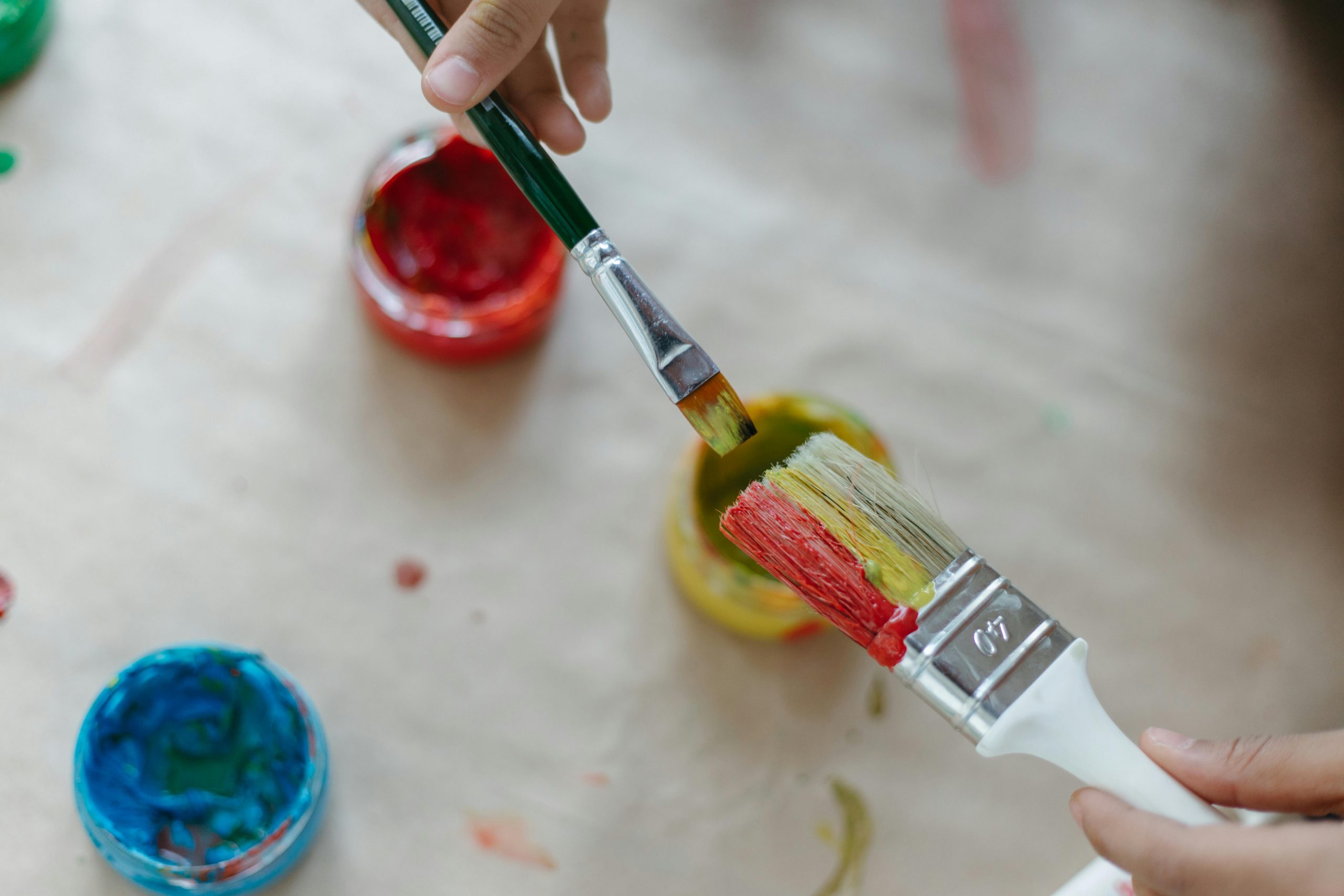 close-up of hands holding one large and one small paintbrush