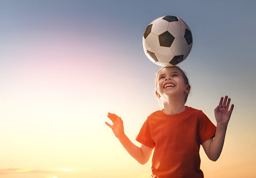little girl balancing a soccer ball on her head
